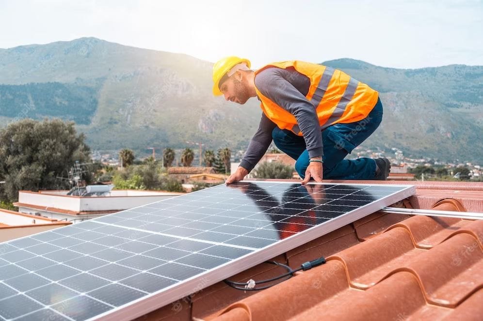 Artisan posant des panneaux photovoltaïque sur le toit d'une maison